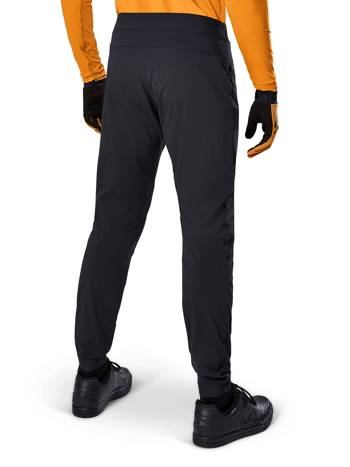 Pantalones Alpinestars A-Dura, pantalones de MTB negros, vista trasera, combinados con un jersey de manga larga naranja y guantes negros, con puños elásticos y material textil duradero para ciclismo de montaña.