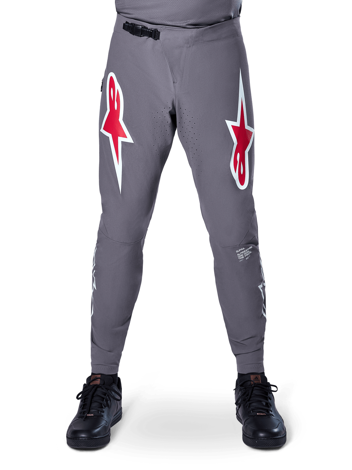 Alpinestars A-Supra Race Pants, pantalones de ciclismo de montaña (MTB), gris oscuro, con grandes logotipos de estrella rojos y blancos en los muslos, ventilación perforada con láser en la parte interna de las piernas y cierre de trinquete negro en la cintura, diseñados para carreras de MTB.