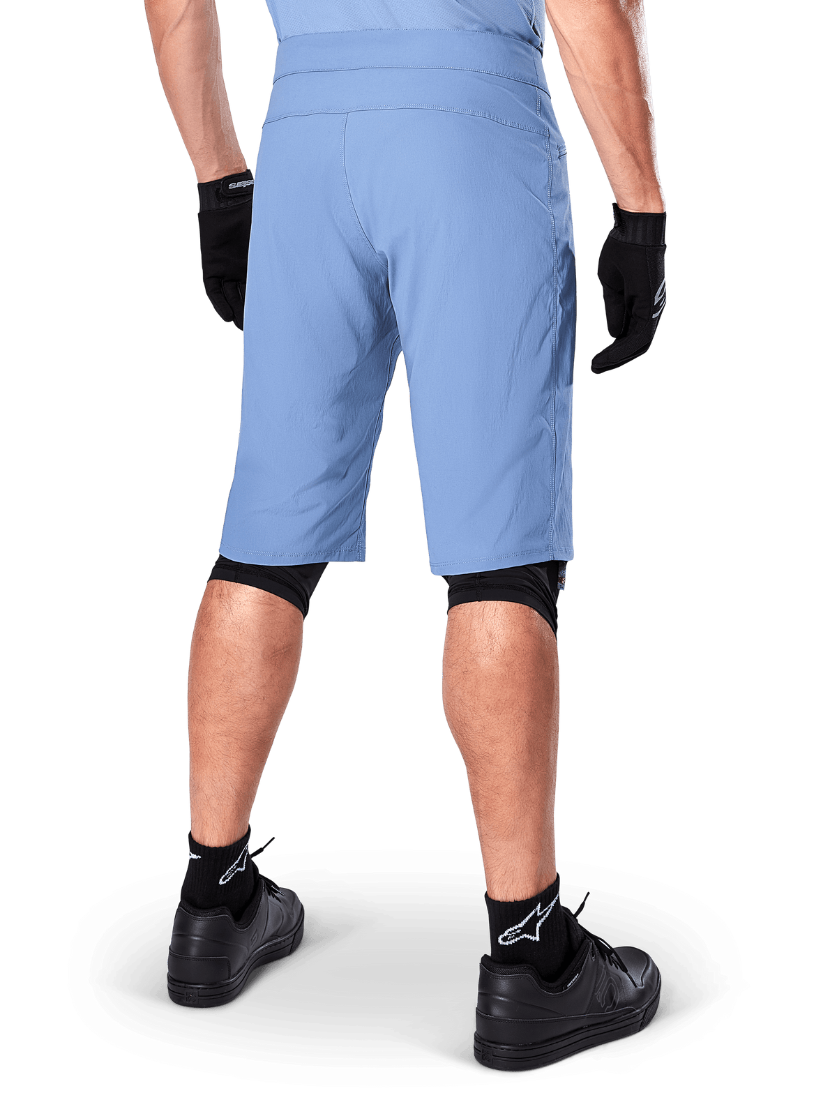 Alpinestars A-Dura Shorts, shorts de mountain bike en color Infinity Blue, vista trasera, combinados con guantes negros, rodilleras y calcetines negros con el logo de la estrella en blanco, material elástico resistente para ciclismo de montaña