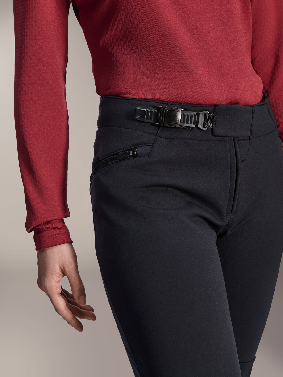Alpinestars Stella A-Dura Thermal Pant, pantalones de MTB para mujer, negros, primer plano del sistema de cierre de trinquete en la cintura y el bolsillo lateral con cremallera, usados con una prenda superior de manga larga de color rojo oscuro, equipamiento duradero para rutas en climas fríos