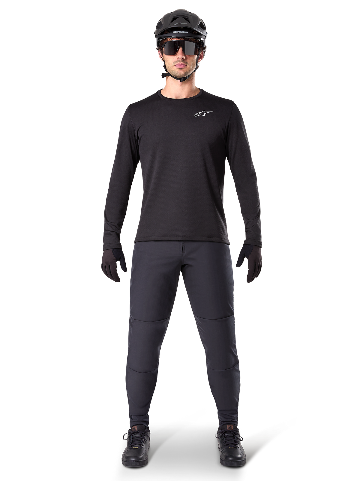 Alpinestars A-Dura Thermal Jersey, jersey de ciclismo de montaña de manga larga, negro, combinado con pantalones gris oscuro, guantes negros, casco negro y gafas de sol, con el logotipo blanco de Alpinestars en el pecho, conjunto coordinado para ciclismo de montaña en climas fríos