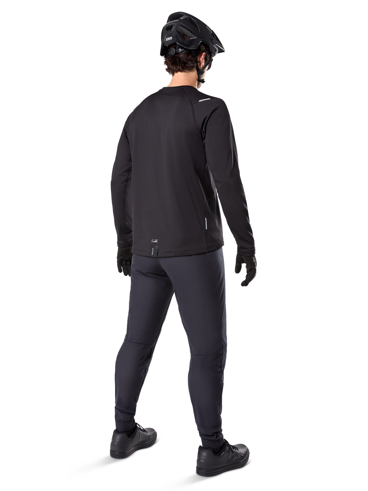 Alpinestars A-Dura Thermal Jersey, jersey de ciclismo de manga larga para hombre, negro, vista trasera del modelo usando casco de MTB negro, pantalones gris oscuro y guantes negros, equipamiento profesional de ciclismo de montaña para clima frío
