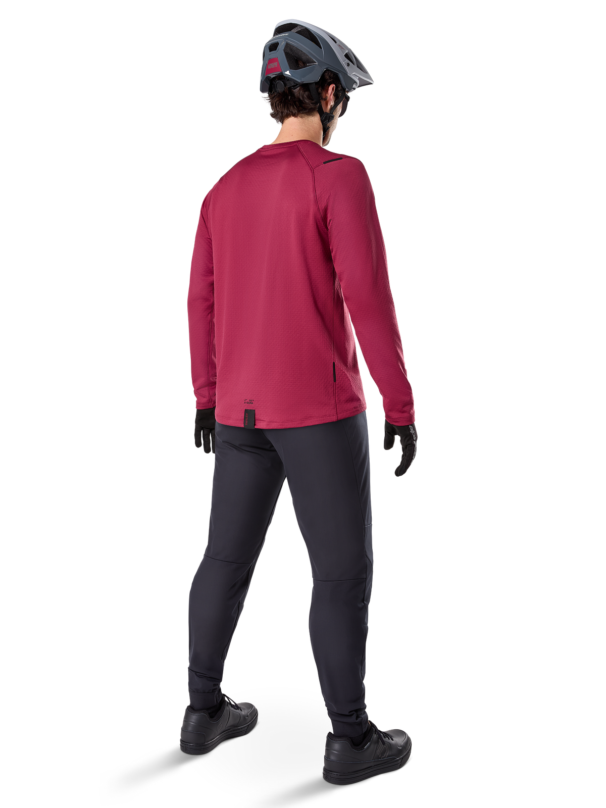Alpinestars A-Dura Thermal Jersey, jersey de ciclismo de manga larga en color burdeos, vista trasera, combinado con pantalones negros de bicicleta de montaña y casco gris, con dobladillo trasero extendido para mayor cobertura, equipamiento de MTB para clima frío