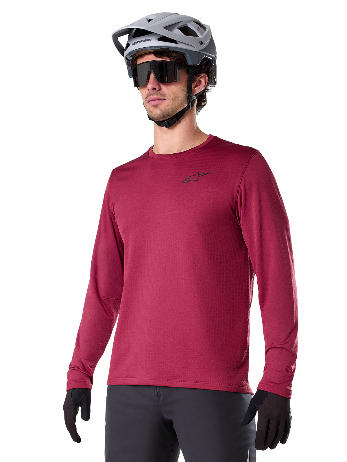 Alpinestars A-Dura Thermal Jersey, jersey de manga larga para ciclismo de montaña, rojo borgoña, con forro polar aislante y un pequeño logotipo negro en el pecho, usado con un casco gris, gafas de sol negras y guantes negros, diseñado para ciclismo en climas fríos