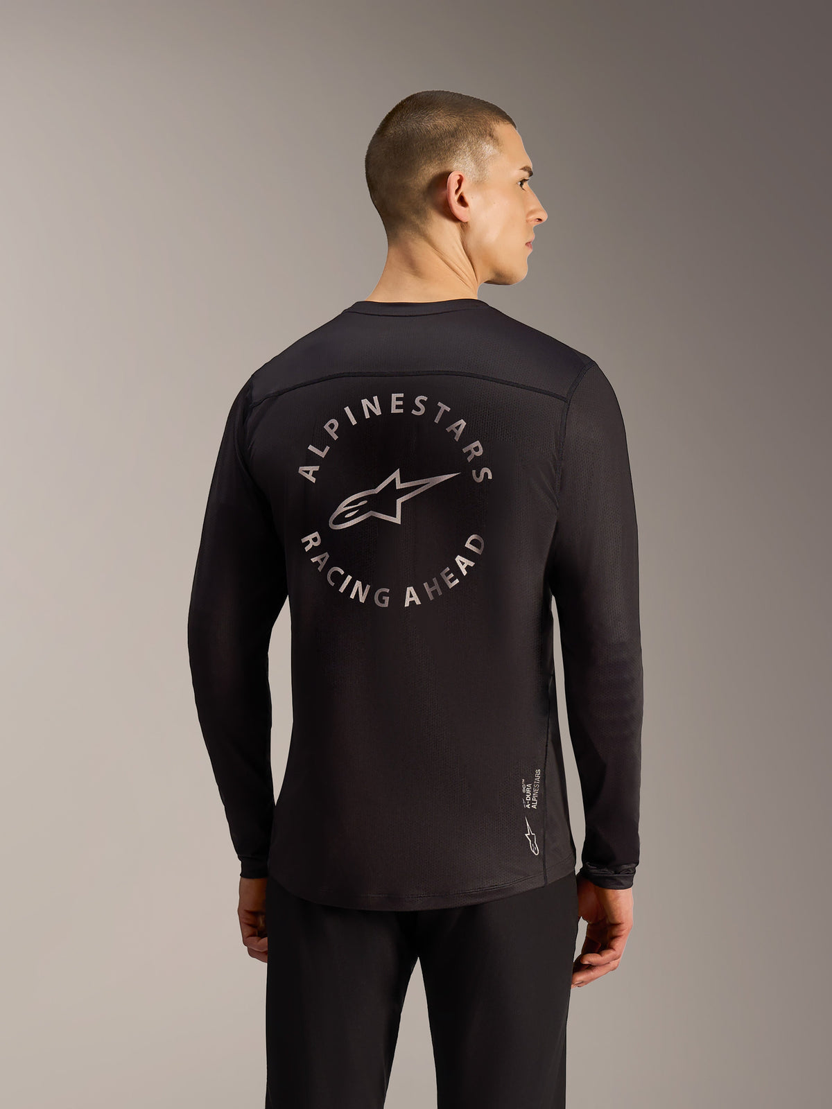 Jersey A-Dura Air negro de manga larga, vista trasera con gráfico circular Alpinestars Racing Ahead y malla transpirable.