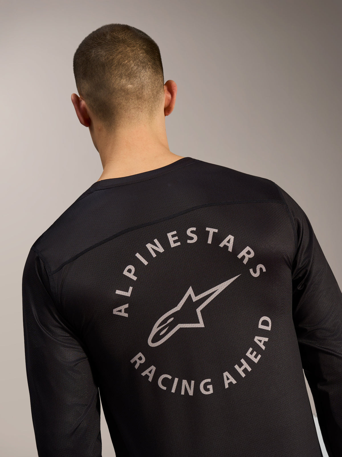 Jersey Alpinestars A-Dura Air negro, detalle posterior con logo circular Racing Ahead sobre tejido de malla transpirable.