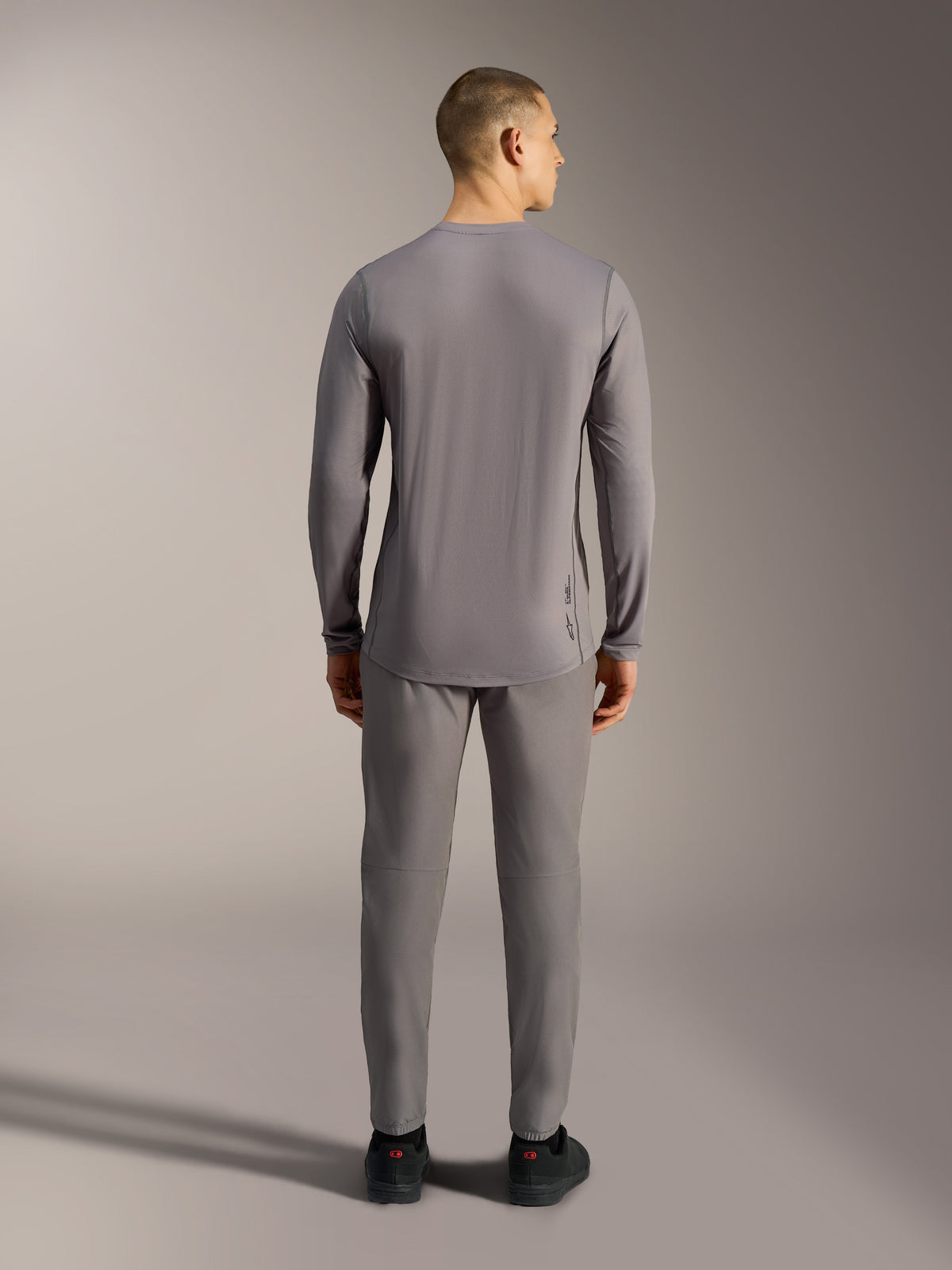 Camiseta Alpinestars A-Dura Ride gris de manga larga para MTB, tejido elástico jacquard y corte trasero más largo.