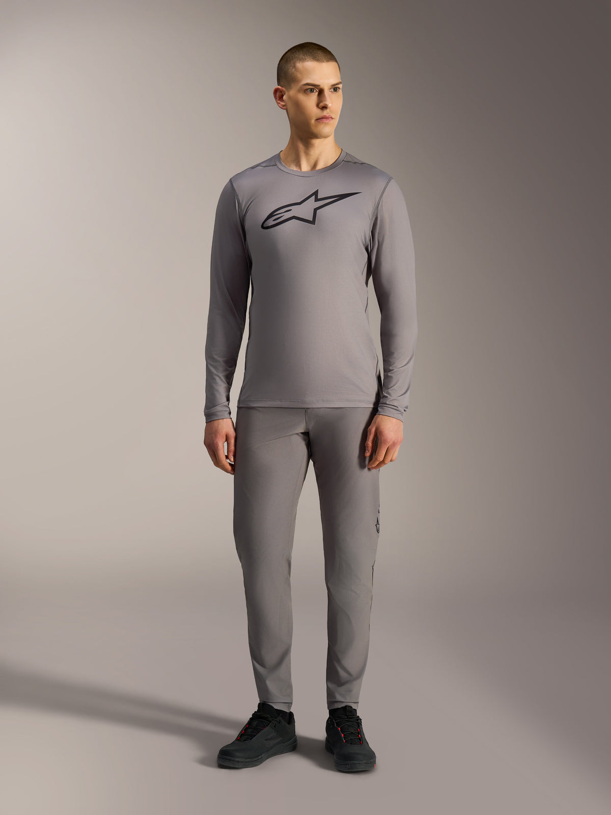 Camiseta Alpinestars A-Dura Ride gris de manga larga, logo negro en el pecho y pantalones de MTB a juego.