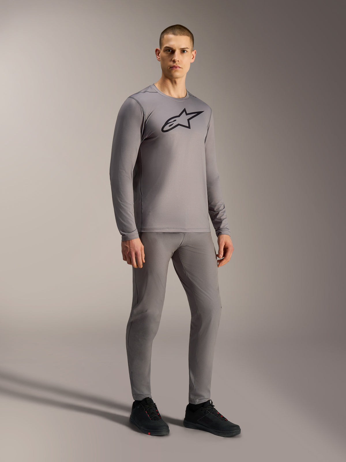 Camiseta Alpinestars A-Dura Ride gris de manga larga con logo negro, en modelo para ciclismo de montaña.