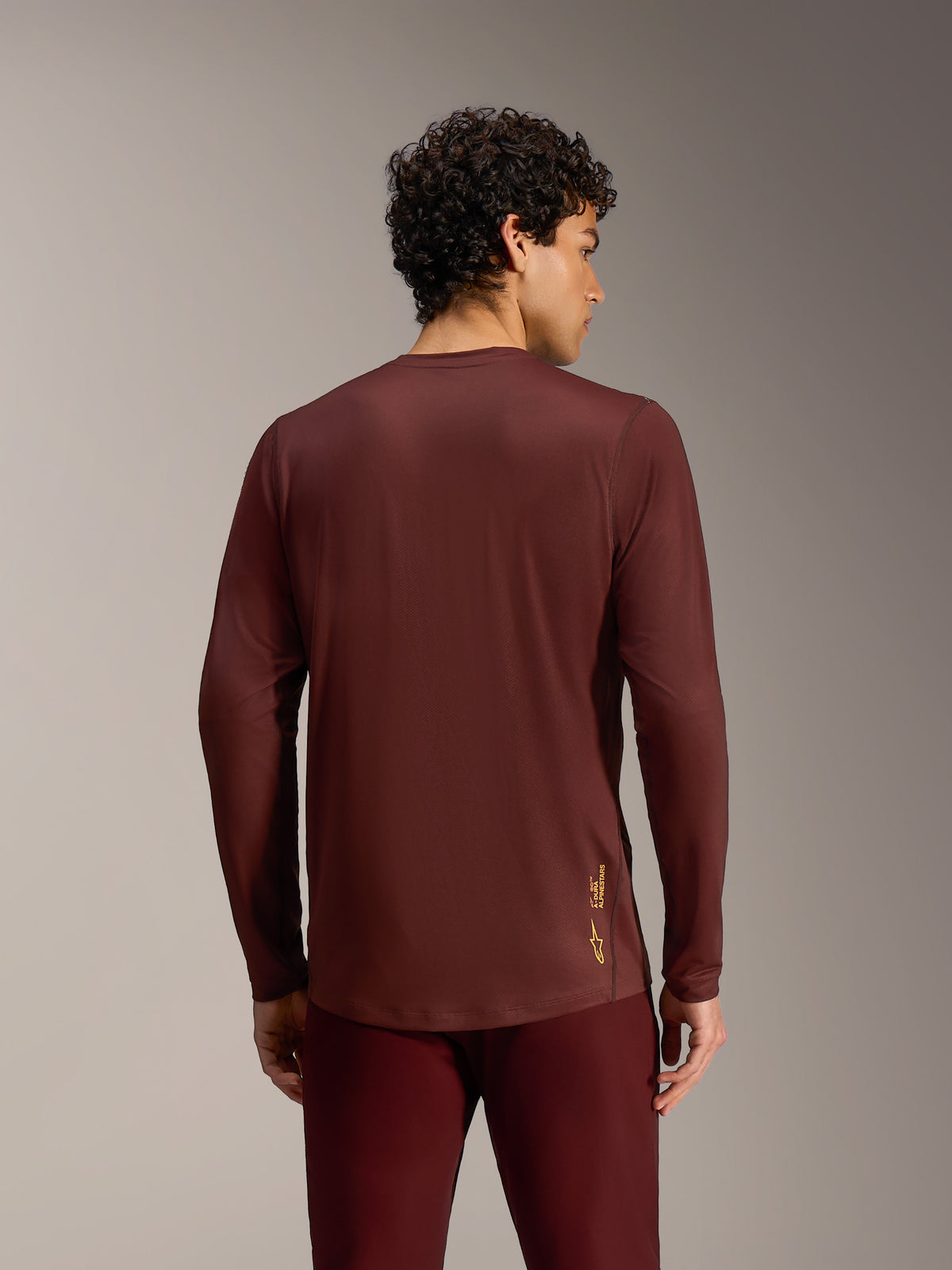Jersey Alpinestars A-Dura Ride burdeos de manga larga, vista trasera con tejido técnico de alto rendimiento y cola caída.