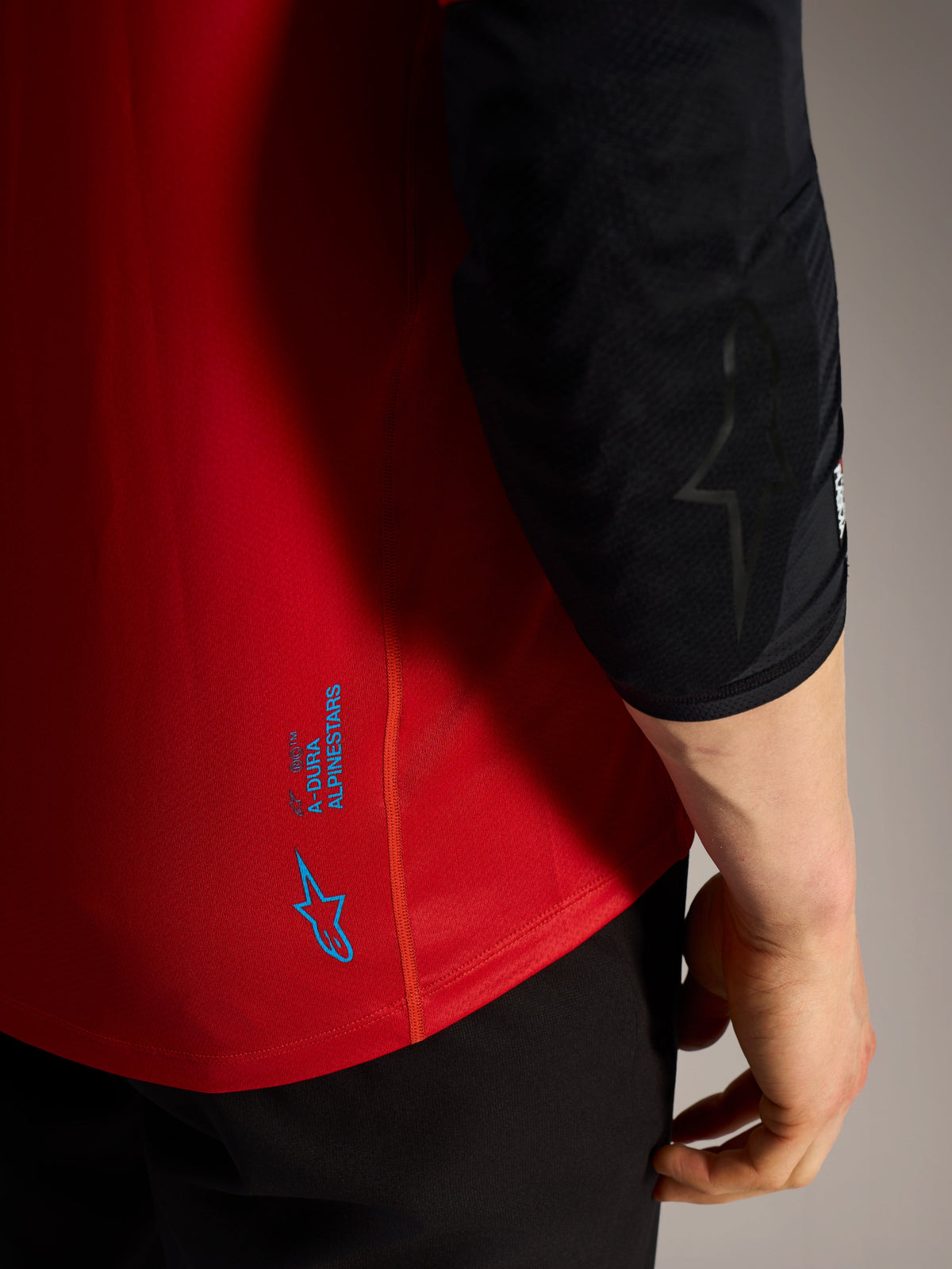 Jersey A-Dura Ride rojo, detalle de logotipos azules Alpinestars y tejido técnico de alto rendimiento para MTB.