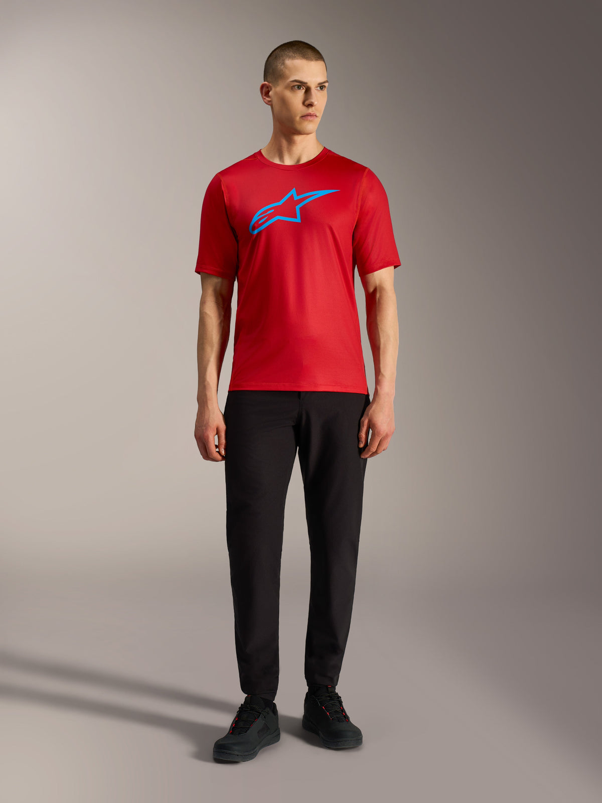 Jersey Alpinestars A-Dura Ride rojo con logotipo azul, combinado con pantalones negros para un estilo MTB casual.