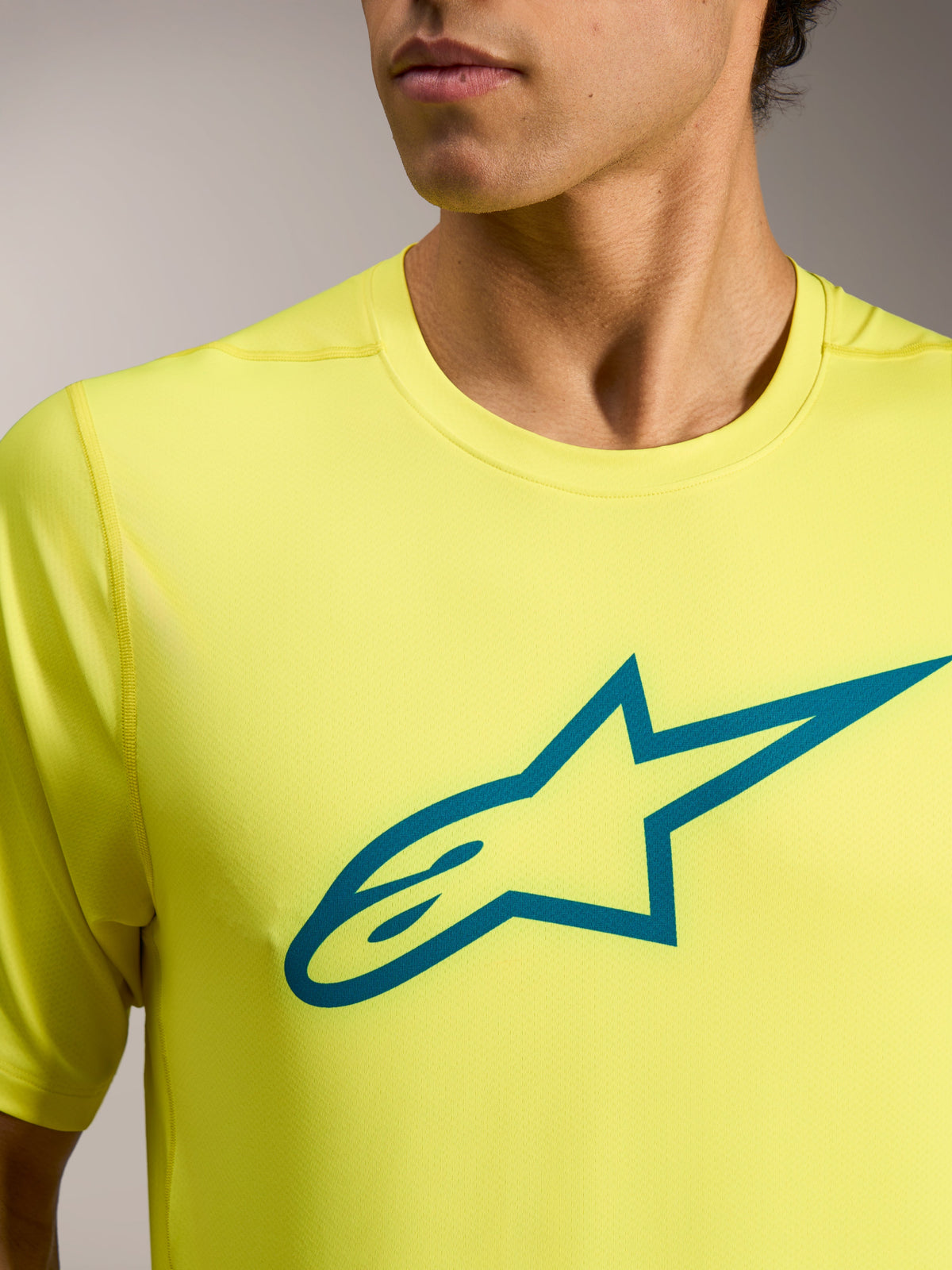 Camiseta A-Dura Ride amarilla flúor con logotipo Astars verde azulado en el pecho, equipación técnica ligera de MTB