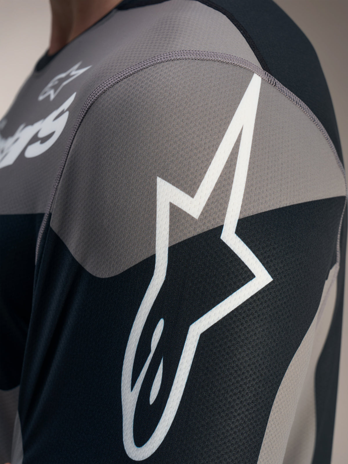 Gray A-Dura Race Long Sleeve Jersey detail showing the white Astars logo on textured, technical jacquard mesh fabric.