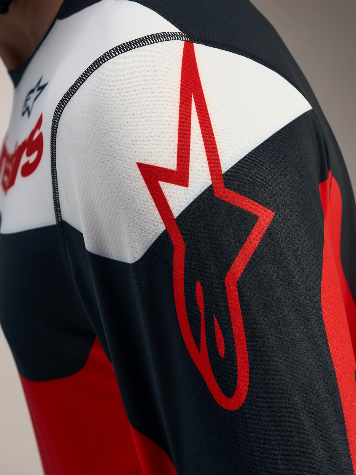 Camiseta A-Dura Race Alpinestars roja y negra, detalle del logo de estrella sobre tejido de malla jacquard transpirable.