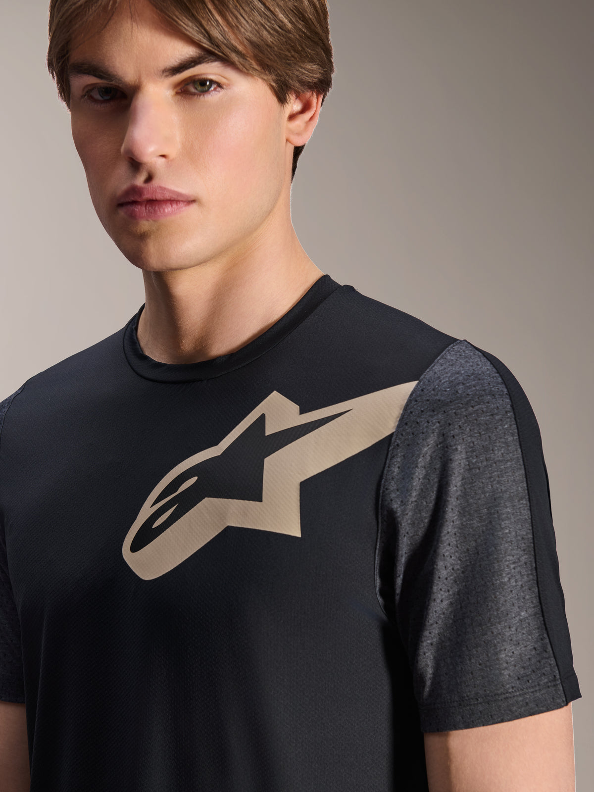 Jersey Alpinestars A-Dura Lipan de manga corta, negro, con el logotipo Astars en color arena en el pecho y mangas perforadas en gris oscuro jaspeado, ropa técnica de alto rendimiento para ciclismo de montaña