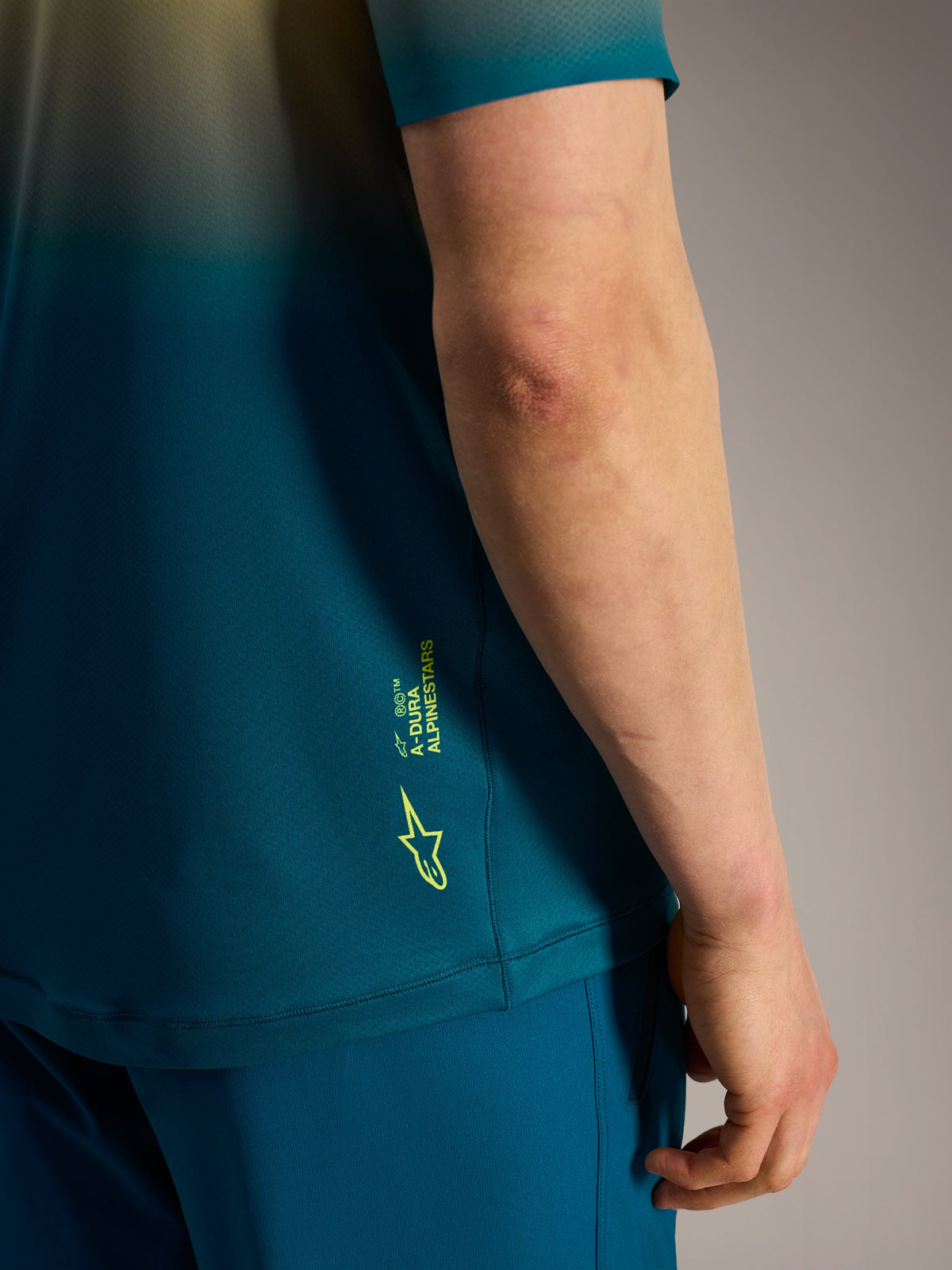 Maillot Alpinestars A-Dura ASTARS 2.0 azul verdoso con logotipo y marca en amarillo flúor en el lateral.