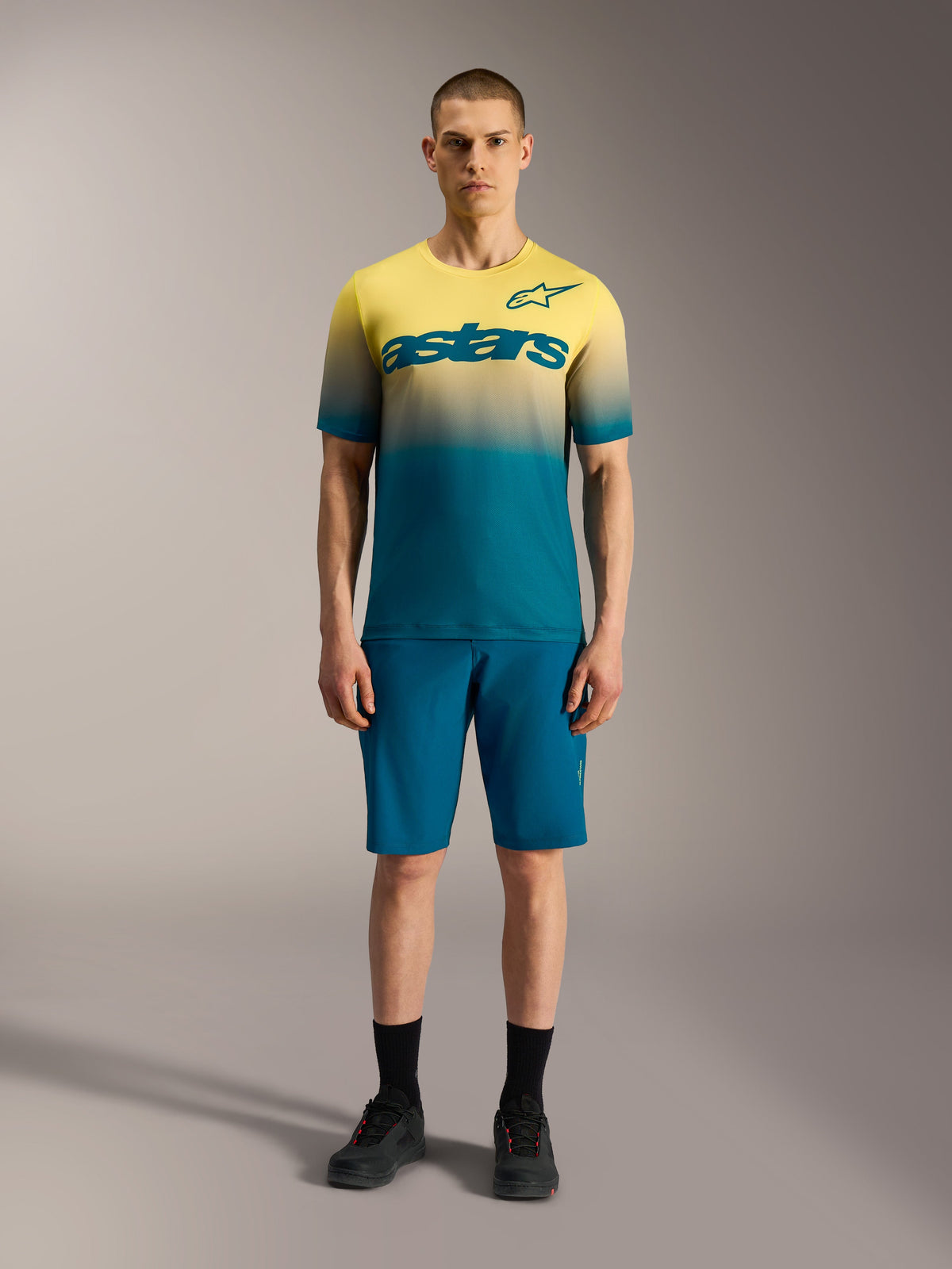 Maillot Alpinestars A-Dura ASTARS 2.0, camiseta de MTB de manga corta con degradado amarillo y azul y logotipo en el pecho