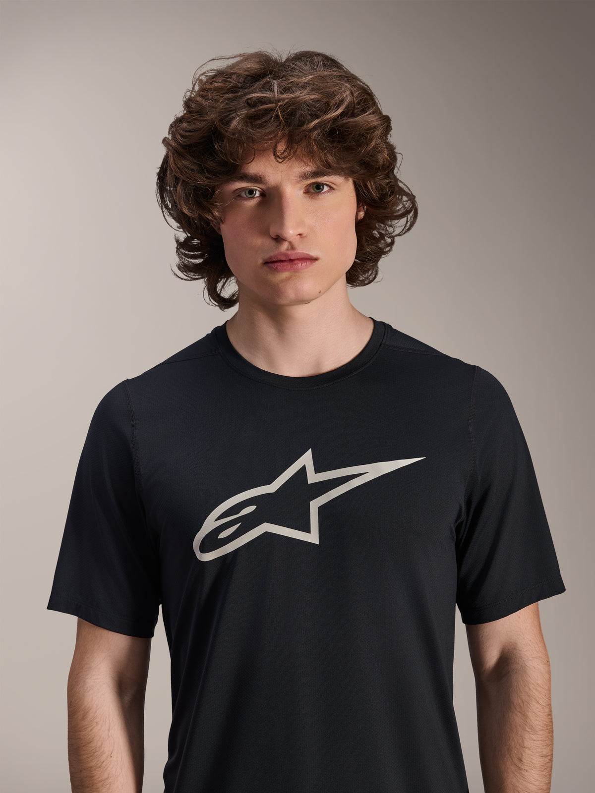 Alpinestars A-Dura Astar Jersey de manga corta, negro, con un gran logotipo Astar blanco en el pecho, usado por un modelo masculino, ropa técnica de mountain bike de estilo casual