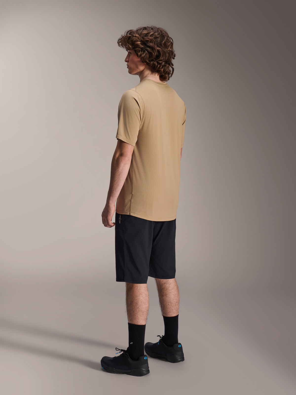 Alpinestars A-Dura Shorts, Mountain Bike Shorts, Black, paired with a tan A-Dura short-sleeve jersey and black riding shoes, featuring a regular fit and durable construction for off-road cycling, rear-side view