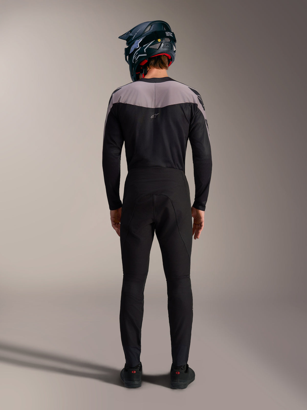 Kit MTB Alpinestars A-Supra Elite negro con jersey, pantalones técnicos y casco integral, vista posterior.