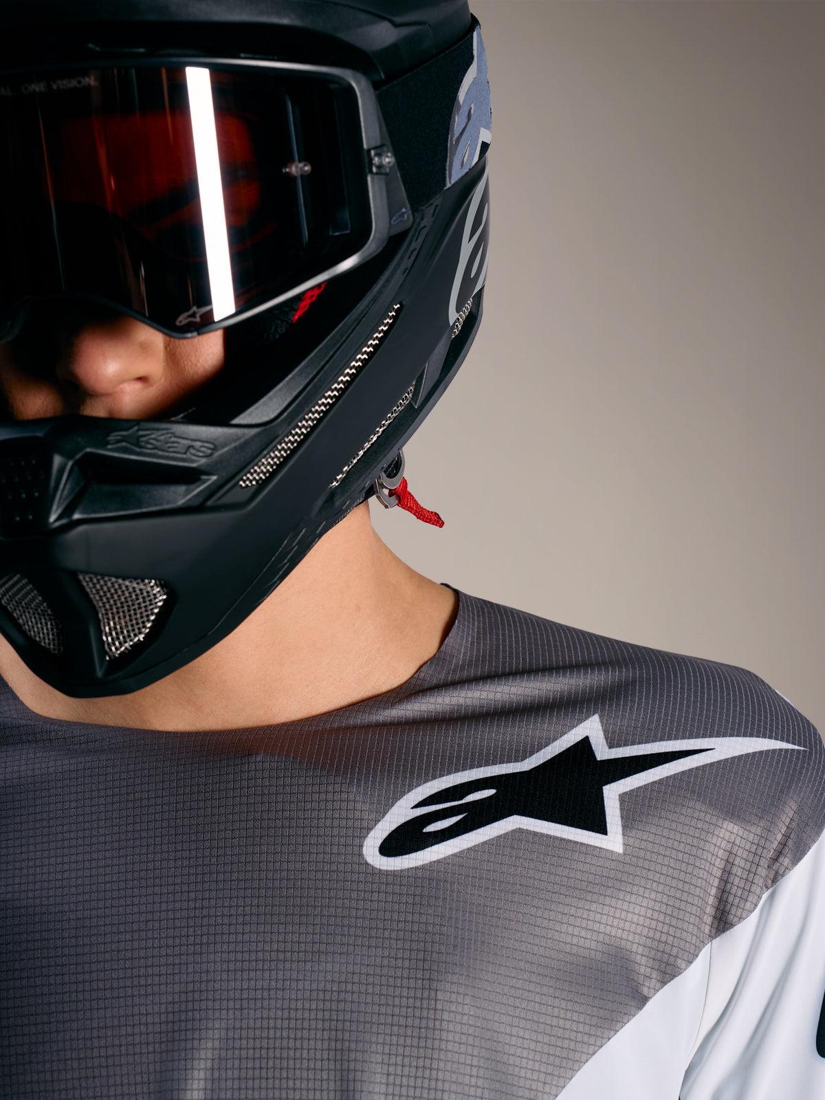 Jersey Alpinestars A-Supra Elite en gris degradado con logo blanco, tejido microperforado y casco de MTB negro.