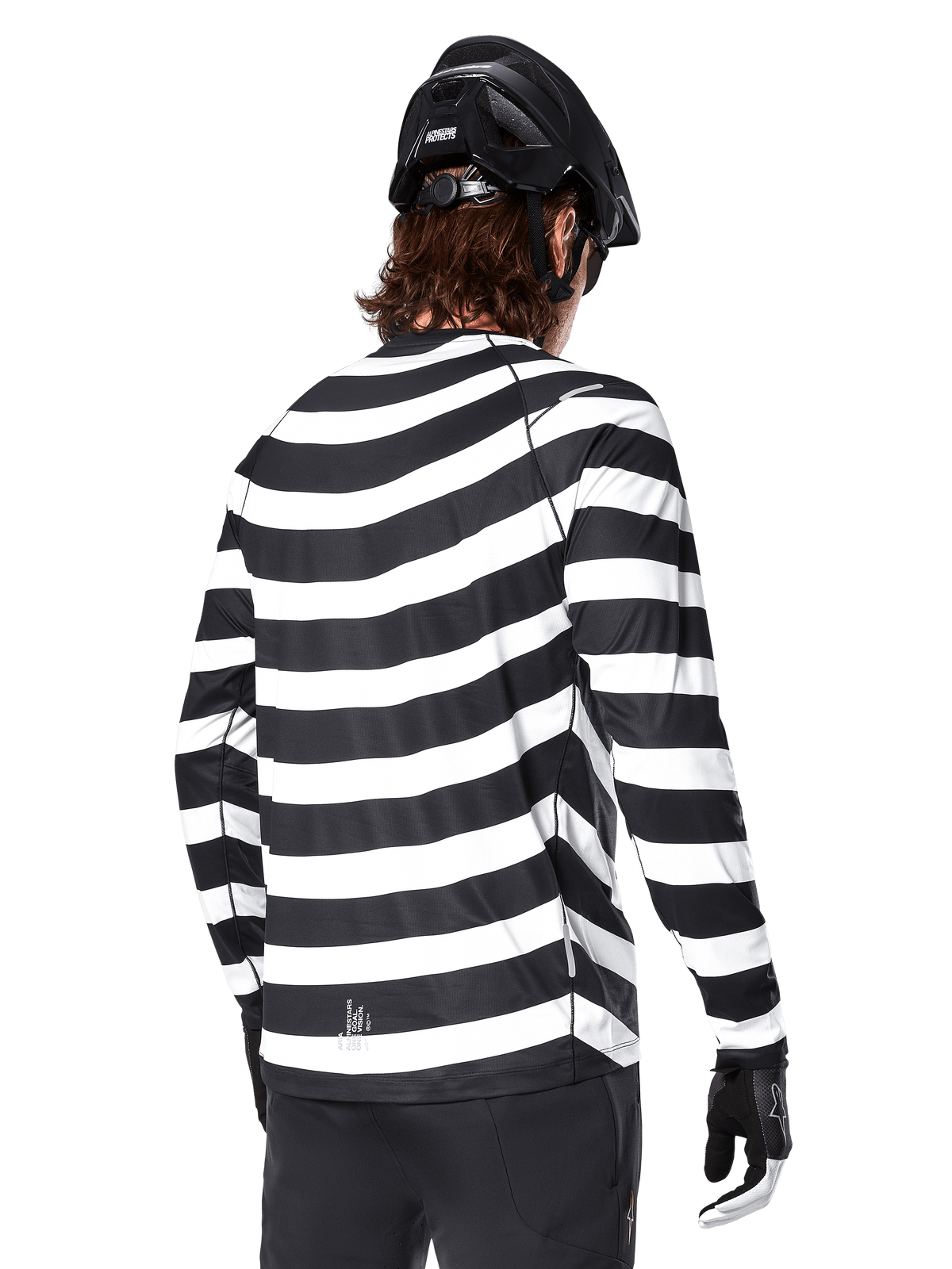Jersey de manga larga Alpinestars A-Aria Oscar, vista trasera, con llamativas rayas horizontales blancas y negras, combinado con un casco de MTB negro y pantalones negros, equipamiento de alto rendimiento para MTB inspirado en el legado de la marca