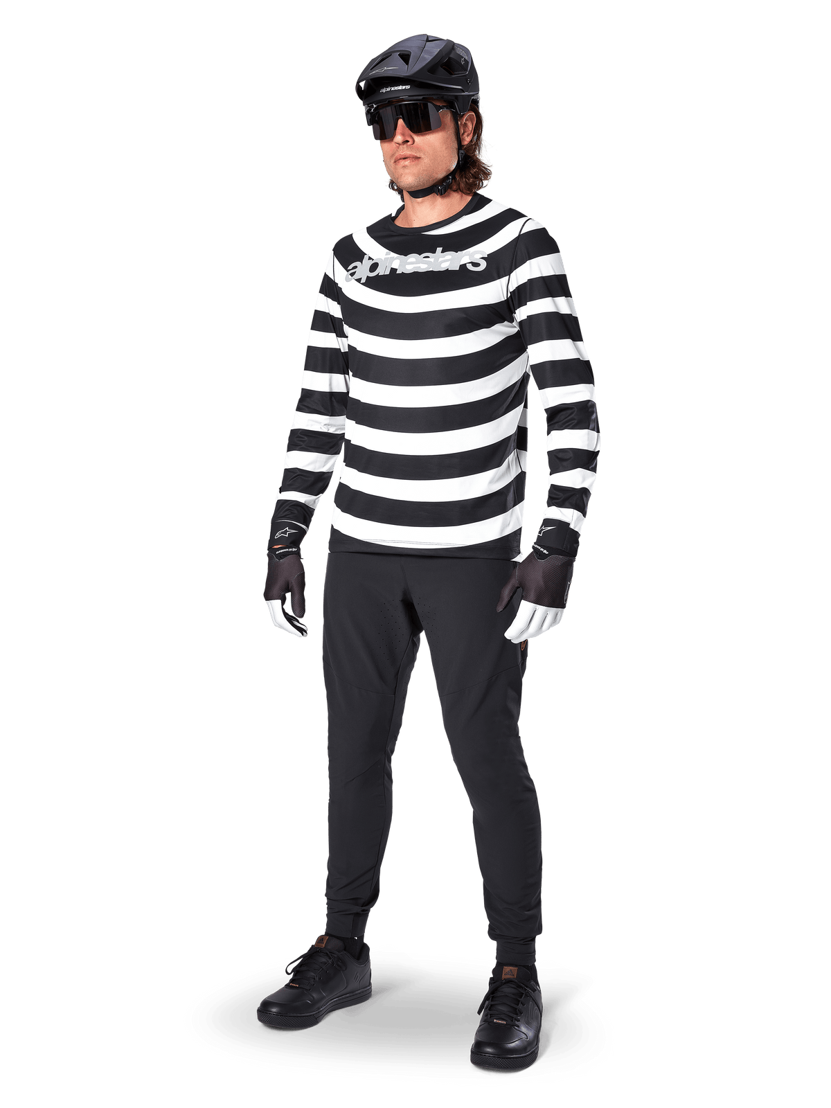Jersey de manga larga Alpinestars A-Aria Oscar, negro y blanco con llamativas franjas horizontales en espiral, logotipo curvo de Alpinestars en blanco, equipamiento de MTB de alto rendimiento usado con pantalones de ciclismo negros y casco