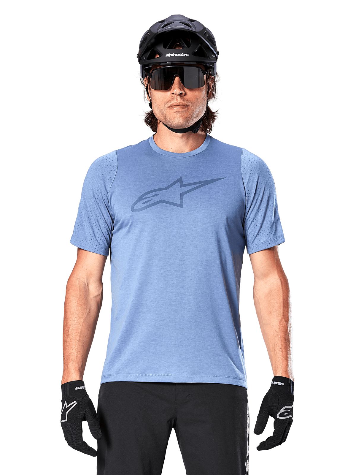 Ciclista de montaña con el jersey de manga corta Alpinestars A-Dura Dri Astar en azul Infinity, con un logotipo sutil en el pecho y paneles de malla, complementado con casco negro, gafas de sol y guantes negros para un conjunto técnico de ciclismo