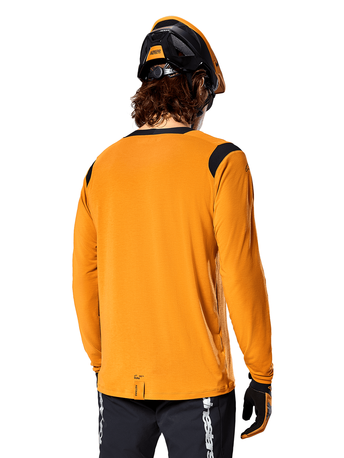 Alpinestars A-Dura Dri Wool Long Sleeve Jersey in Dark Gold, back view of a rider wearing a mountain bike helmet and gloves, featuring black mesh panels on the shoulders and a longer drop tail, technical cycling apparel for trail riding
