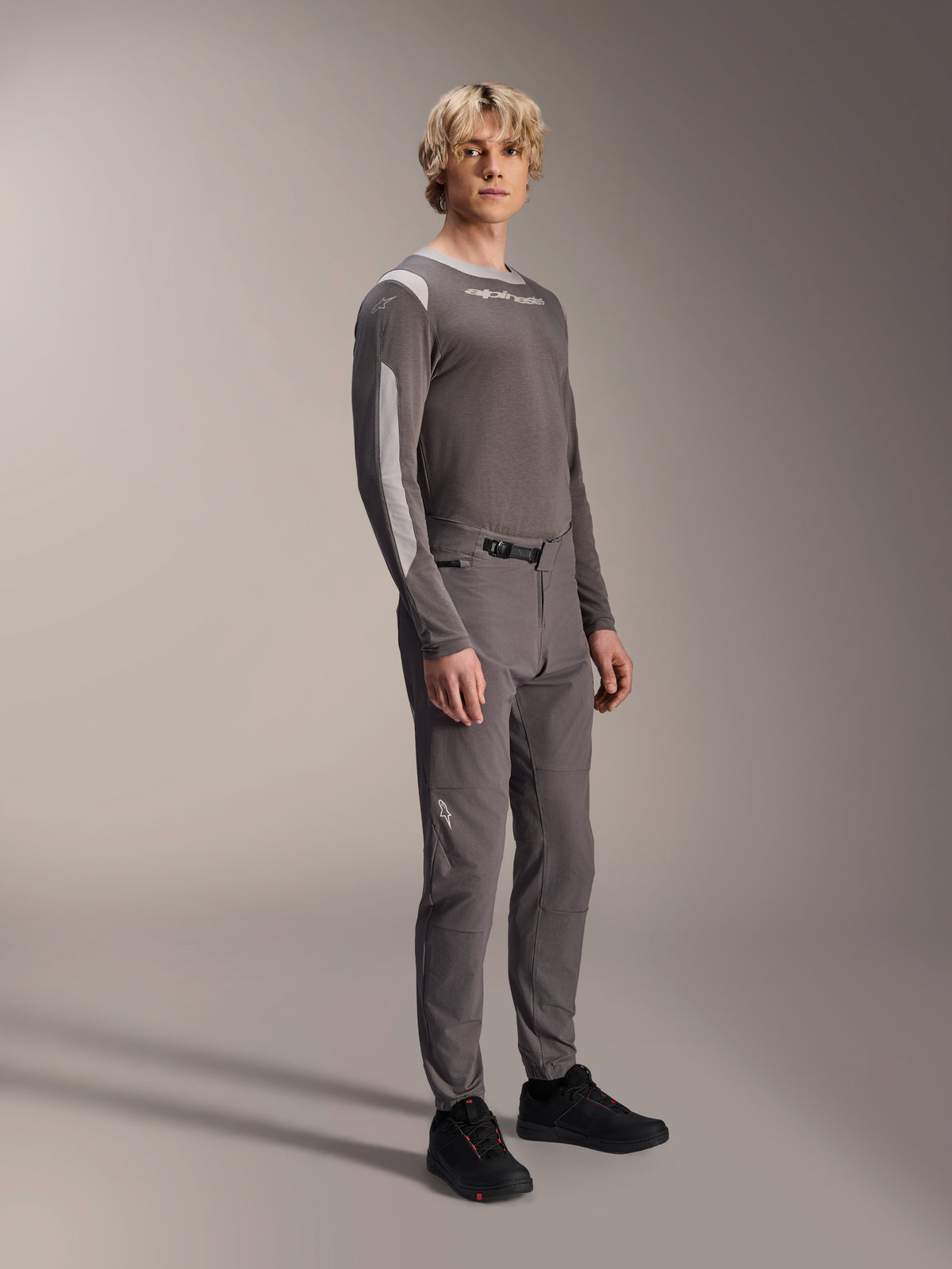 Pantalones Alpinestars A-Dura Elite, pantalones de mountain bike, gris oscuro, usados con un jersey de manga larga a juego y calzado negro, con cierre de trinquete frontal y tejido Cordura resistente para trail y enduro