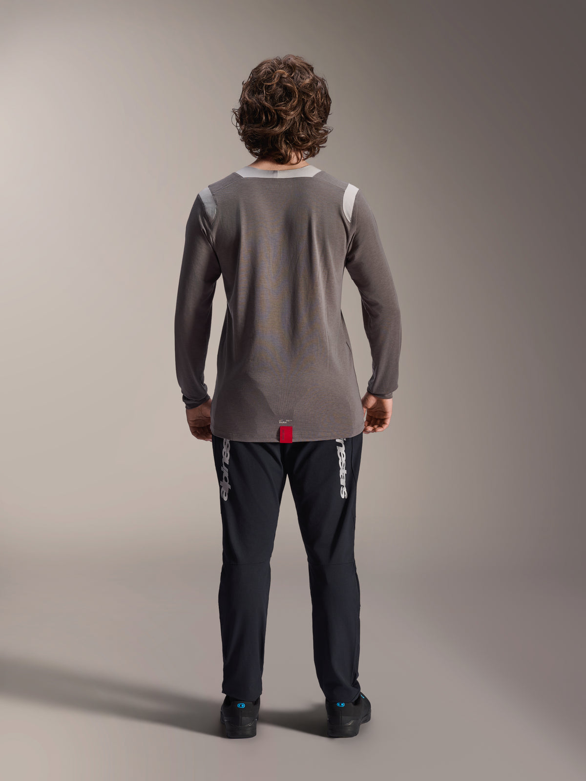Alpinestars A-Dura Elite Pants y Jersey de manga larga A-Dura Dri Wool, pantalones negros con logotipos blancos, jersey técnico gris, vista trasera de equipamiento para bicicleta de montaña, ropa de ciclismo todoterreno duradera