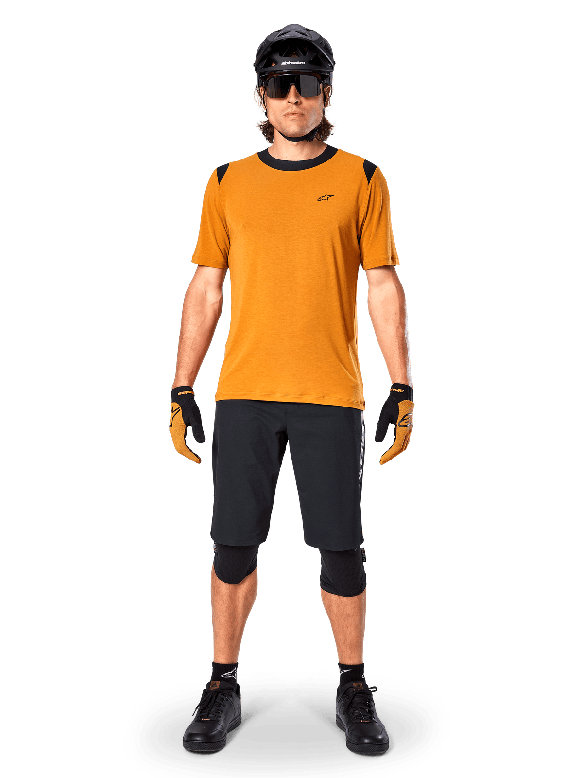 Jersey de manga corta Alpinestars A-Dura Dri Wool en color Dark Gold, jersey de mountain bike usado con pantalones cortos negros y equipo de protección, tejido amarillo mostaza con cuello y detalles en los hombros en negro, ropa de ciclismo de alto rendimiento para rodar por senderos.