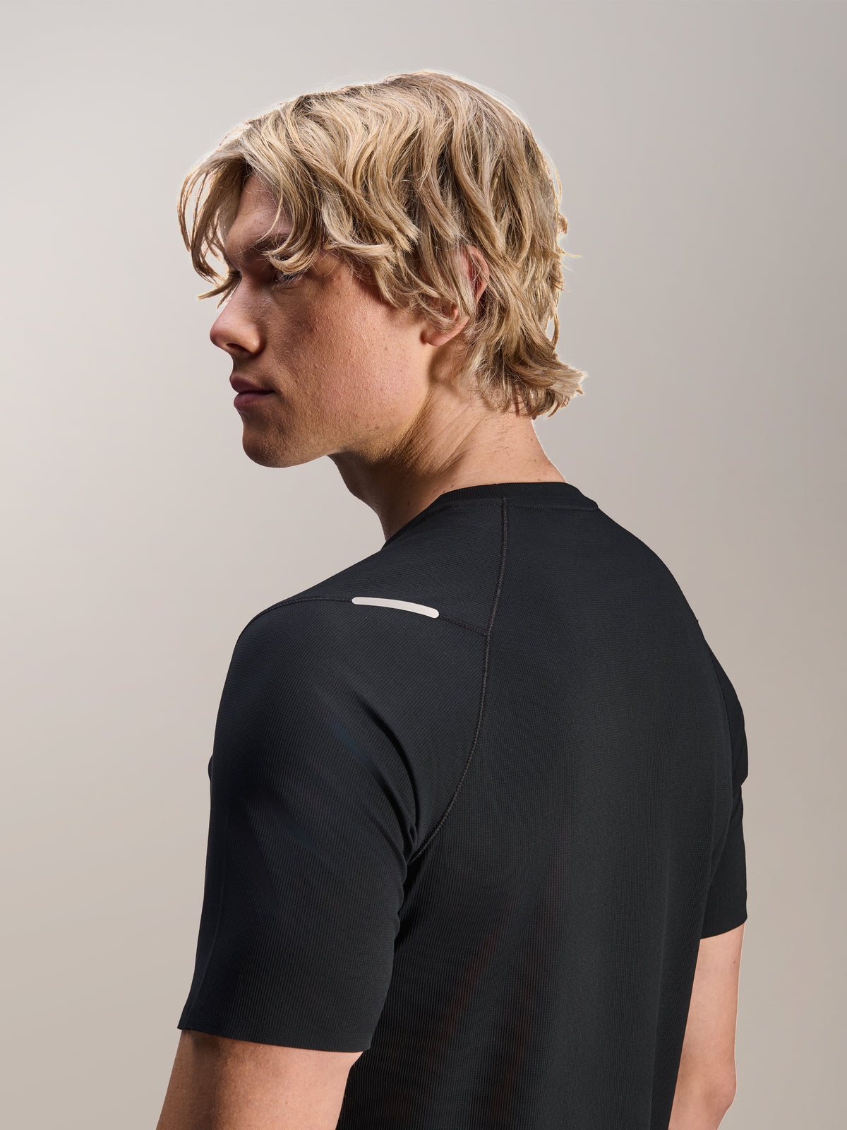 Hombre usando el Jersey Alpinestars A-Aria Switch de manga corta en color negro, vista lateral y posterior mostrando el ajuste de rendimiento y el detalle del hombro, ropa de ciclismo MTB ligera y transpirable