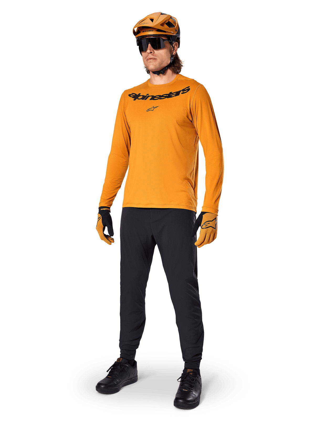 Alpinestars A-Dura Rocker Long Sleeve Jersey, jersey de ciclismo en color Dark Gold, usado con casco de MTB a juego y pantalones negros, con logotipo de la marca negro en el pecho, equipamiento de alto rendimiento para ciclismo de montaña todoterreno