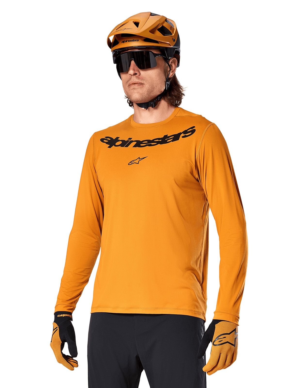 Alpinestars A-Dura Rocker Jersey de manga larga, camiseta para ciclismo de montaña MTB, color oro oscuro, persona con jersey, casco y guantes a juego, look deportivo coordinado con el logotipo de Alpinestars en el pecho