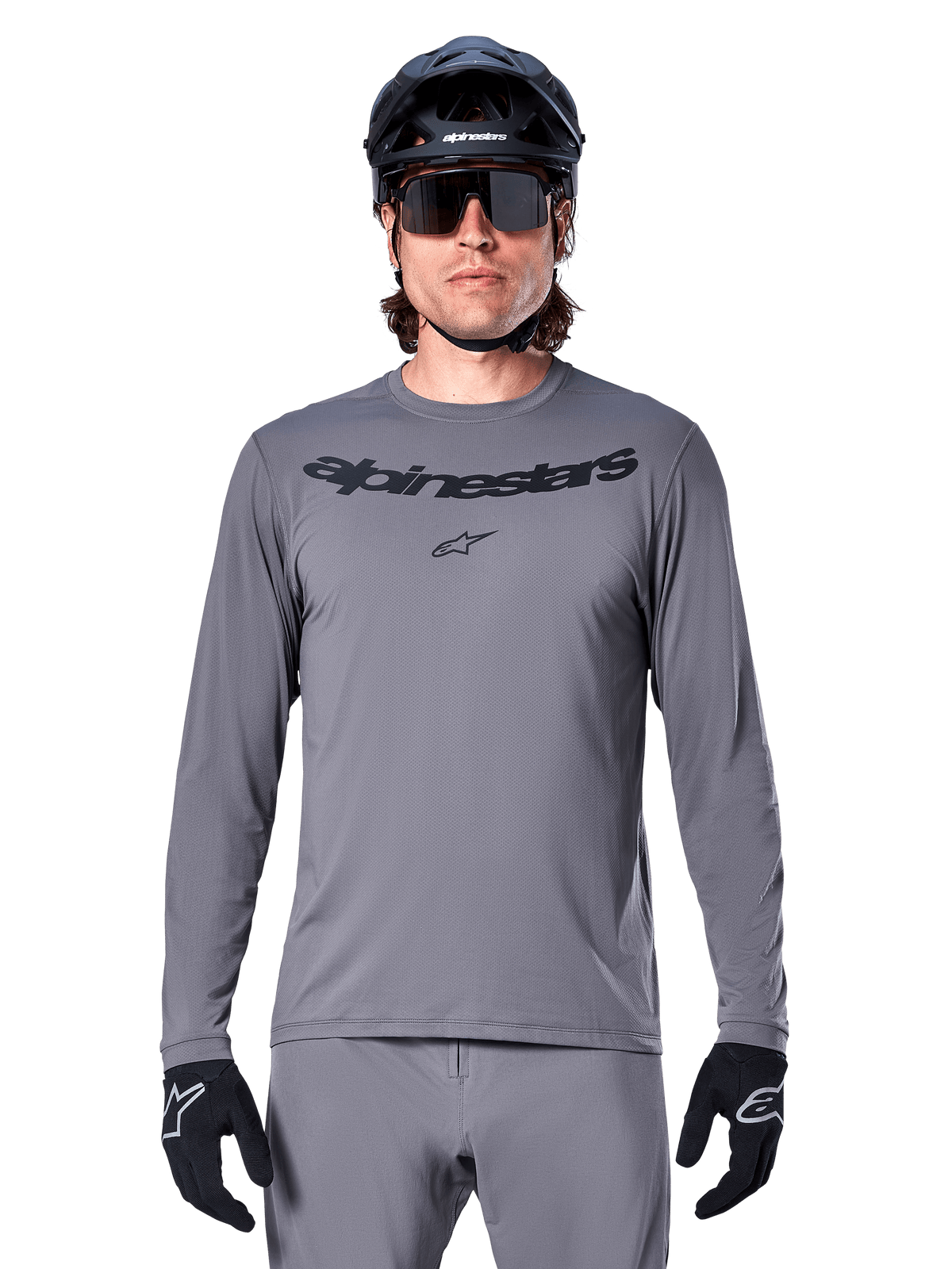 Alpinestars A-Dura Rocker Long Sleeve Jersey, jersey de MTB para hombre en gris oscuro con logotipo negro en el pecho, combinado con pantalones grises, casco negro y guantes, diseñado para ciclismo de montaña