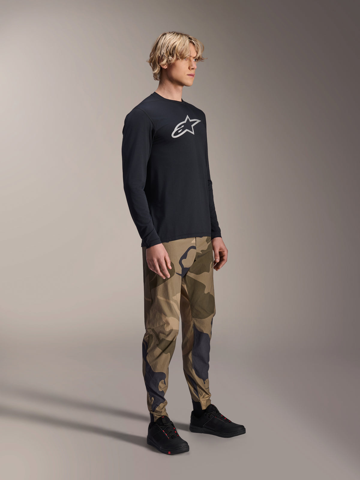 Pantalón Alpinestars A-Dura Camo, pantalones de MTB, camuflaje marrón, usado con un jersey de manga larga A-Dura Astar negro y zapatillas negras, ropa técnica de ciclismo de montaña para trail.