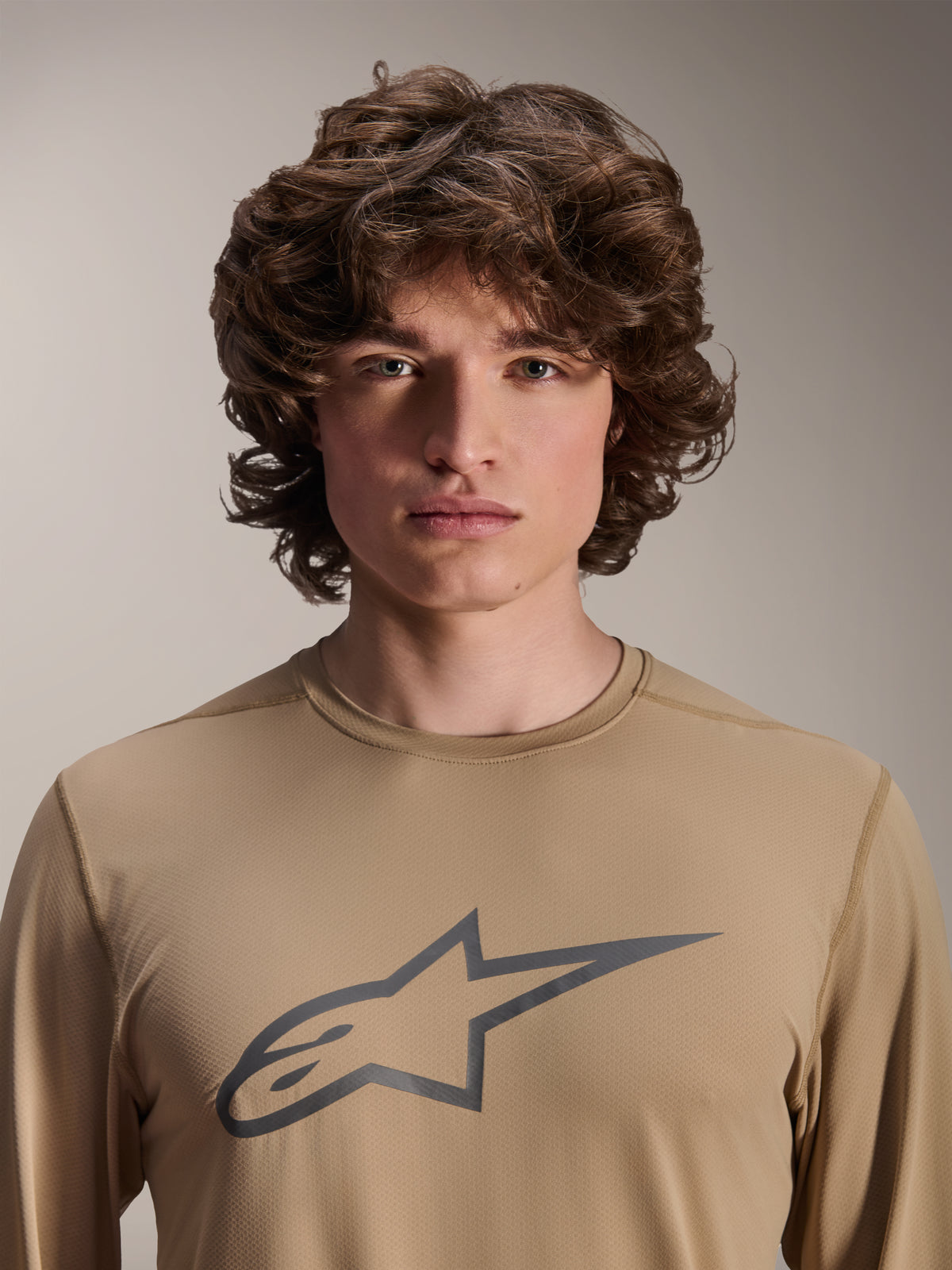 Alpinestars A-Dura Astar Long Sleeve Jersey, marrón claro, usado por modelo masculino, con un gran logotipo de Astars en el pecho, textura de tejido jacquard, ropa casual para ciclismo de montaña