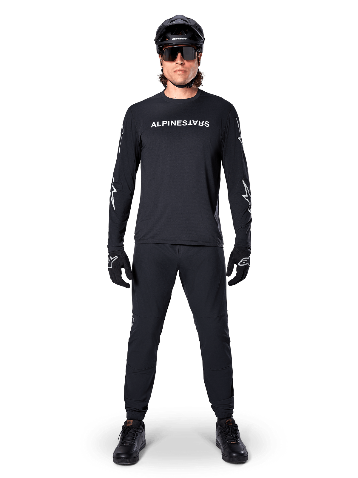 Alpinestars A-Dura Switch Long Sleeve Jersey, Black, worn by a mountain bike rider with matching black pants and helmet, featuring white wordmark logo on the chest, technical off-road cycling apparel
