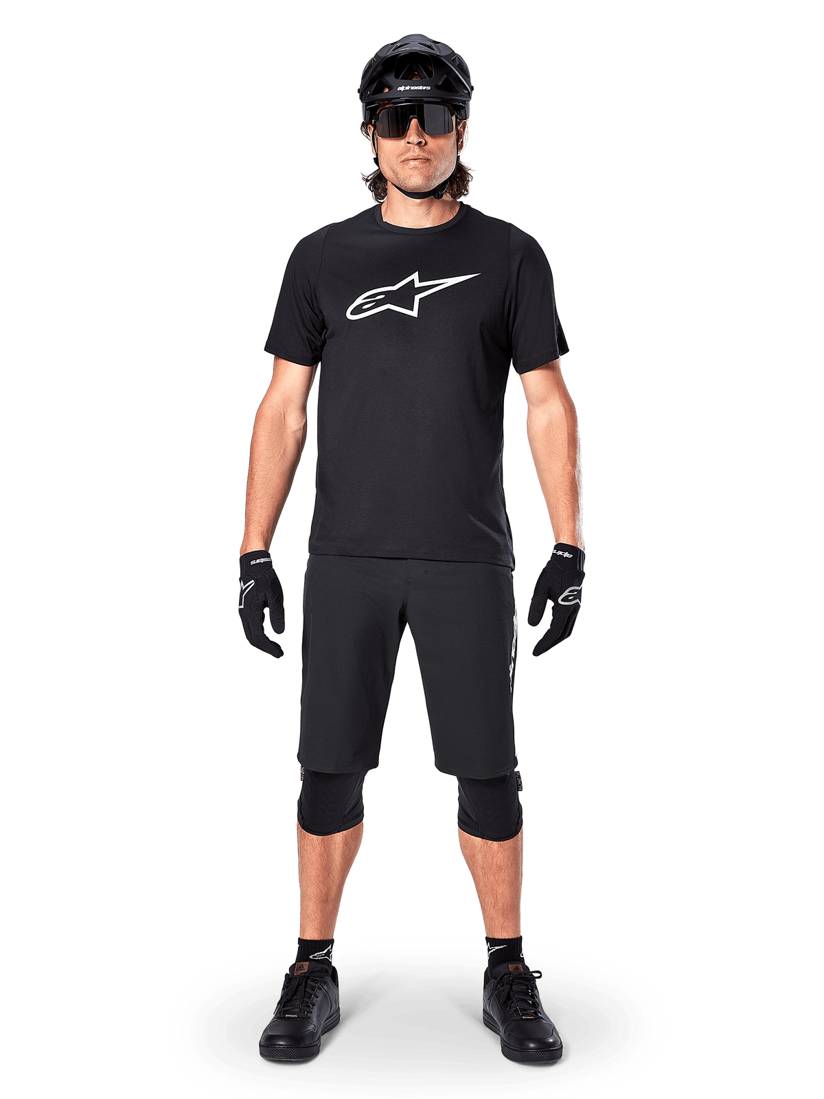 Jersey de manga corta Alpinestars A-Dura Dri Oscar, negro reflectante, combinado con pantalones cortos de MTB, guantes, rodilleras y casco negros a juego, con un gran logotipo de Alpinestars blanco en el pecho, equipamiento completo de ciclismo de montaña