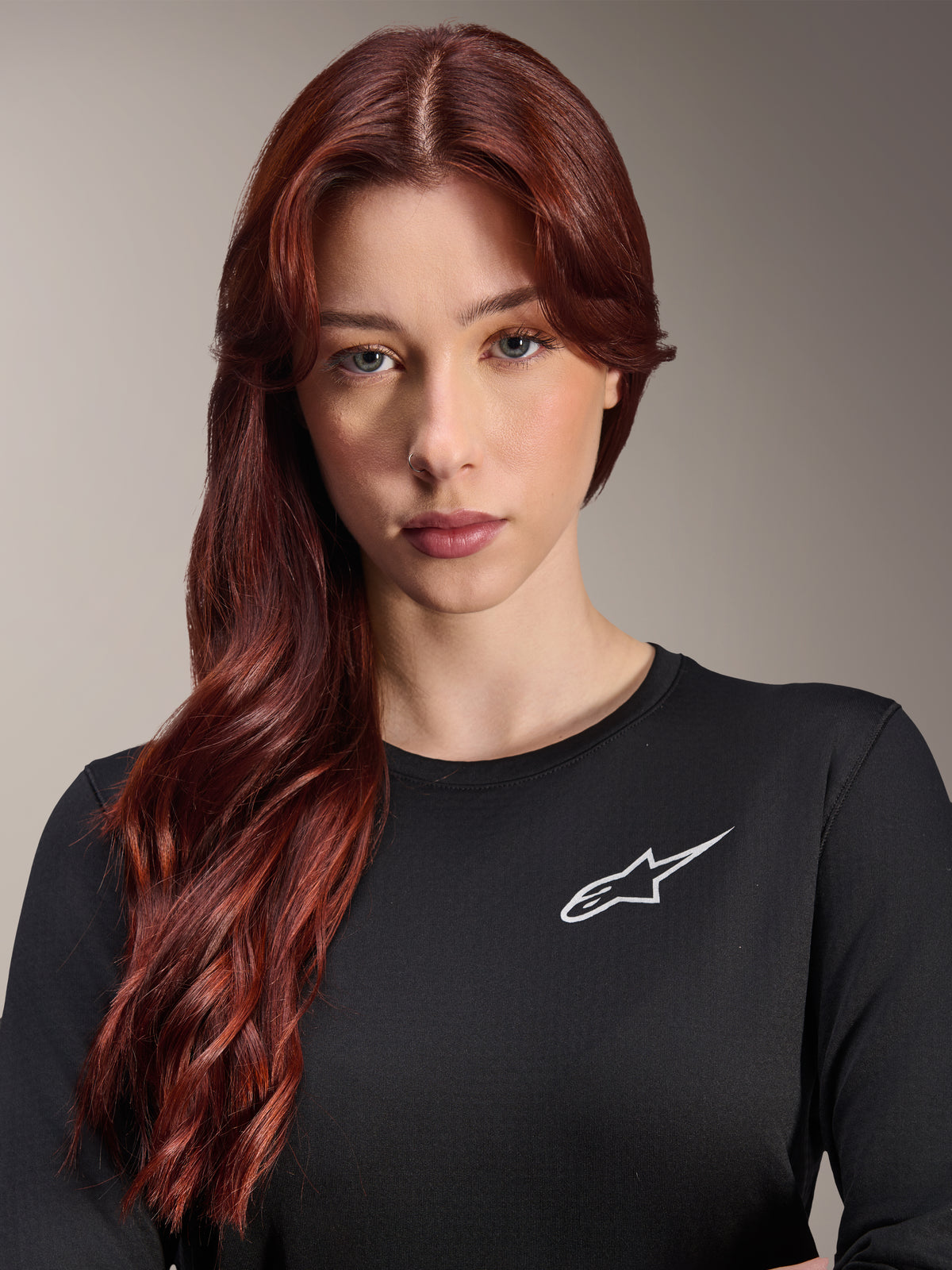 Alpinestars Stella A-Dura Thermal Jersey, Women's Long-Sleeve MTB Jersey, Black with white A-star logo on the chest, close-up portrait of a woman with long red hair, cycling apparel for cool weather.