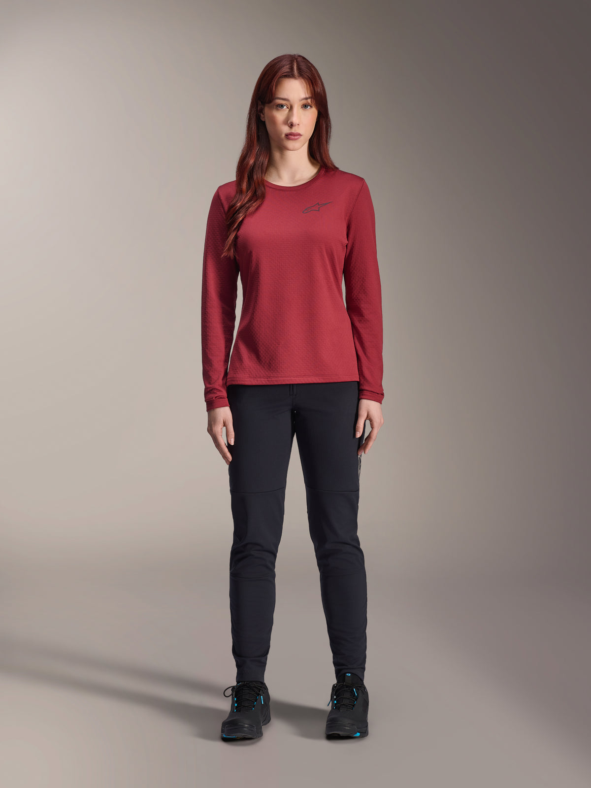 Alpinestars Stella A-Dura Thermal Jersey para mujer, jersey de ciclismo de manga larga, color burdeos, lucido por una modelo con pantalones y calzado negros, cuenta con un logotipo sutil en el pecho, ajuste regular para ciclismo de montaña