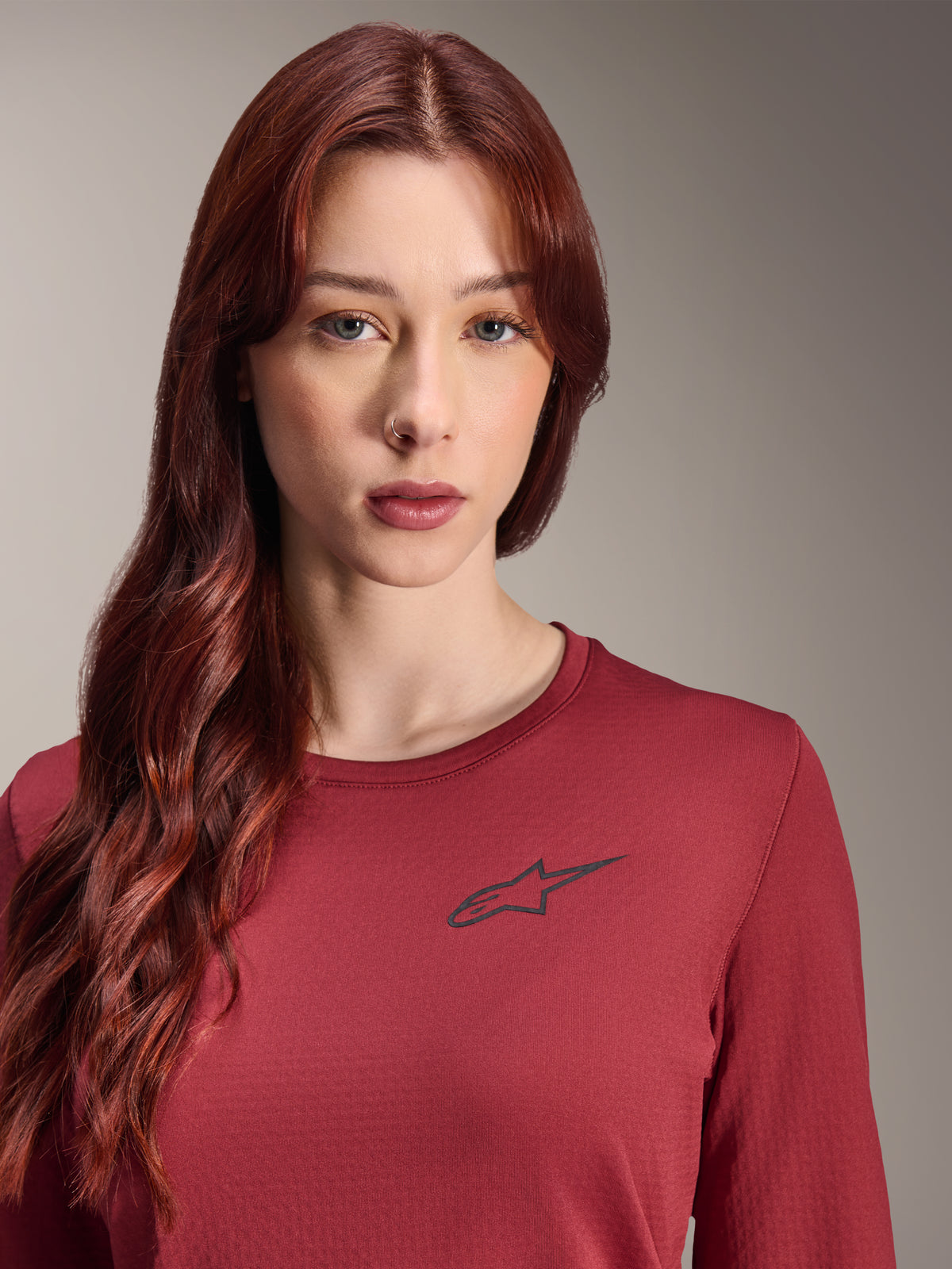 Jersey térmico Alpinestars Stella A-Dura, jersey de MTB de manga larga para mujer, color borgoña, vista de cerca con el logotipo de la estrella negra en el pecho, equipamiento técnico con aislamiento para ciclismo de montaña en climas fríos.