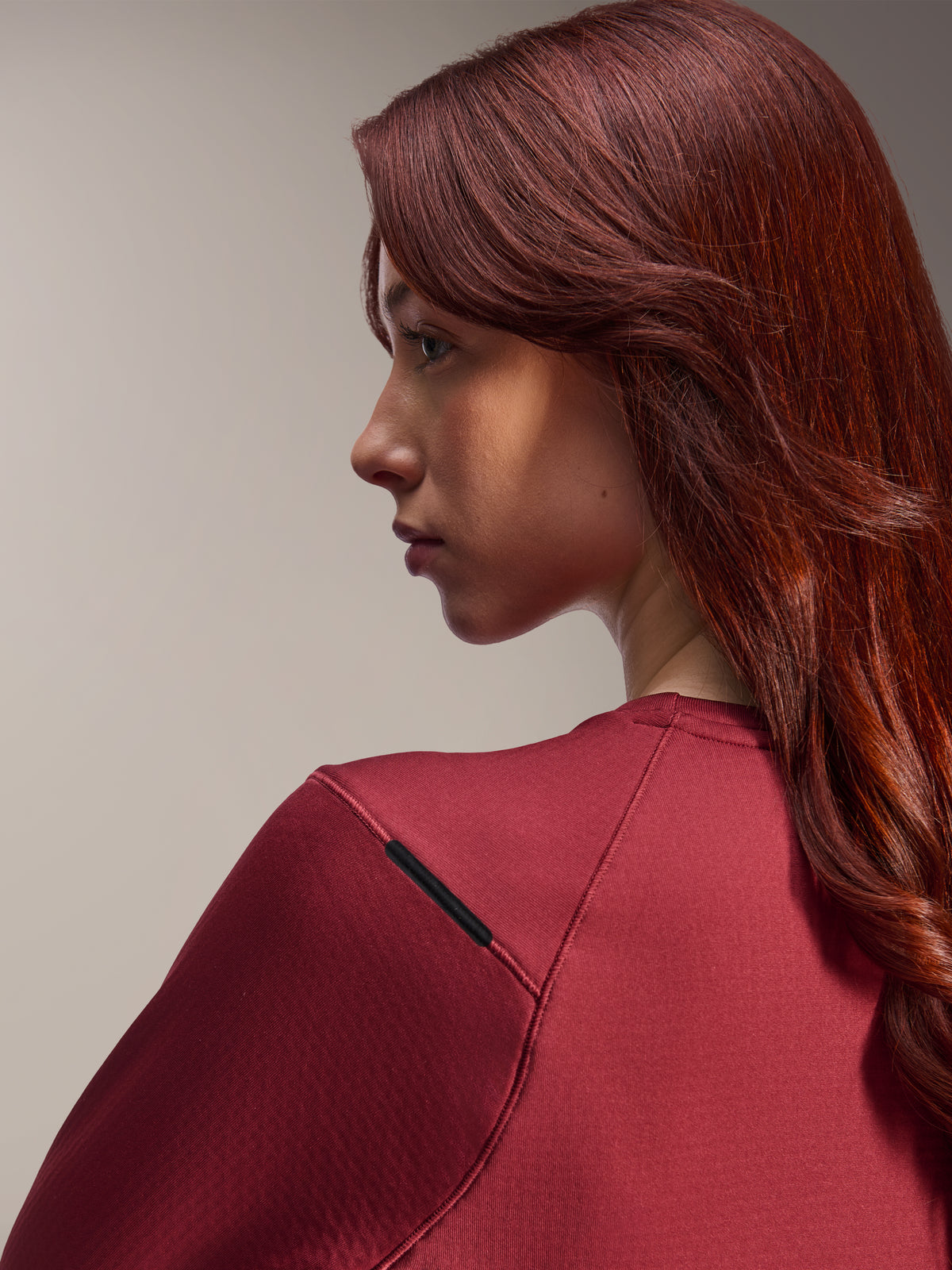 Mujer vistiendo el Jersey Térmico Stella A-Dura de Alpinestars, jersey de MTB de manga larga color granate, primer plano de perfil lateral, enfoque en el detalle de la costura del hombro y la textura del material, equipamiento de ciclismo
