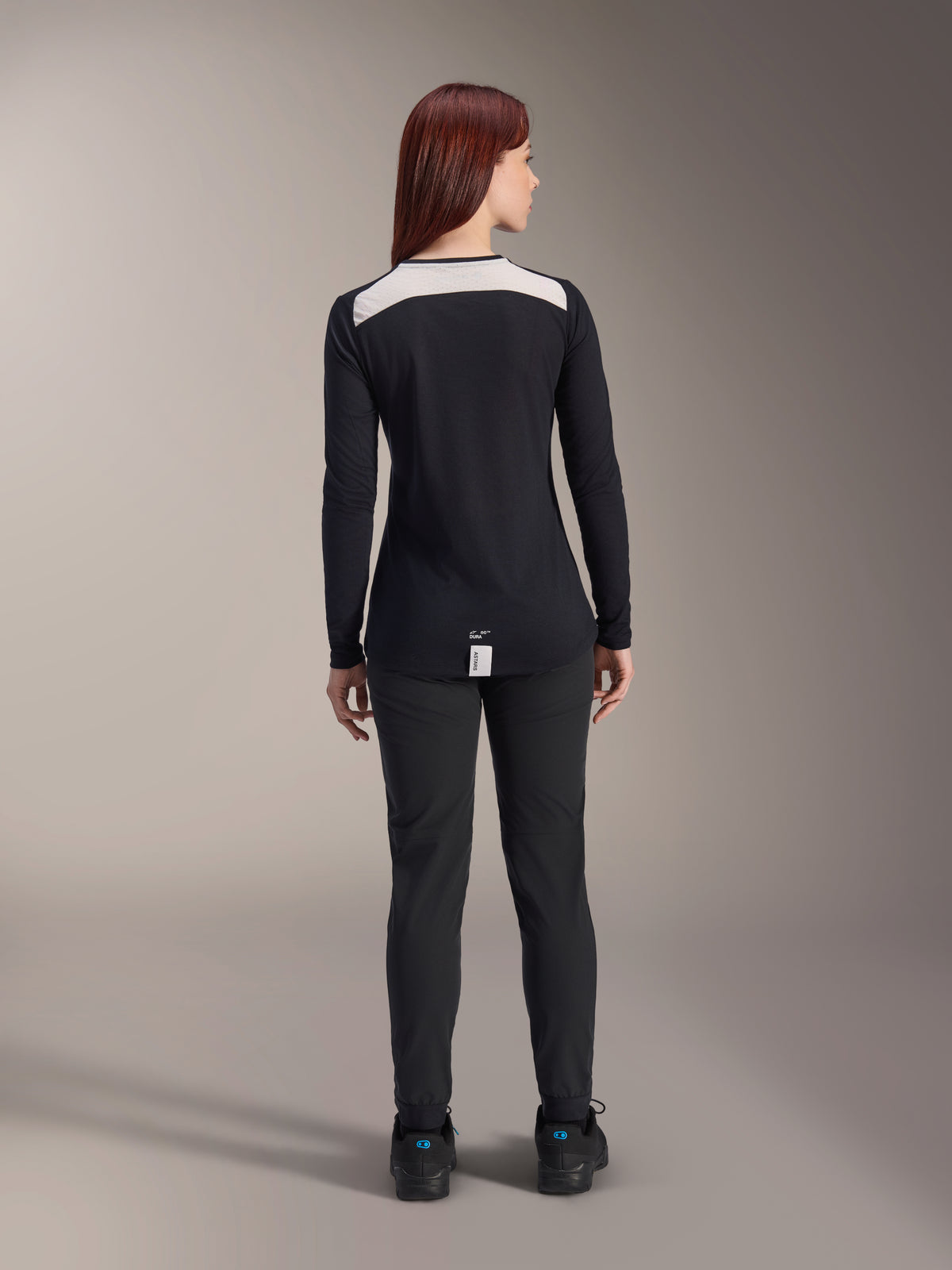 Alpinestars Stella A-Dura Pants y Jersey Stella A-Dura Elite para mujer, equipamiento para MTB, color negro con panel blanco en los hombros, visto desde atrás, ropa técnica de exterior para ciclismo de montaña, combinado con calzado negro