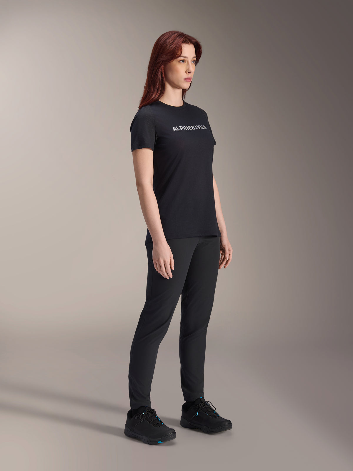 Alpinestars Stella A-Dura Dri Switch Jersey, jersey de ciclismo de manga corta, negro con logo de Alpinestars en blanco, usado por modelo femenina con pantalones y calzado negros a juego, equipamiento versátil para ciclismo de montaña