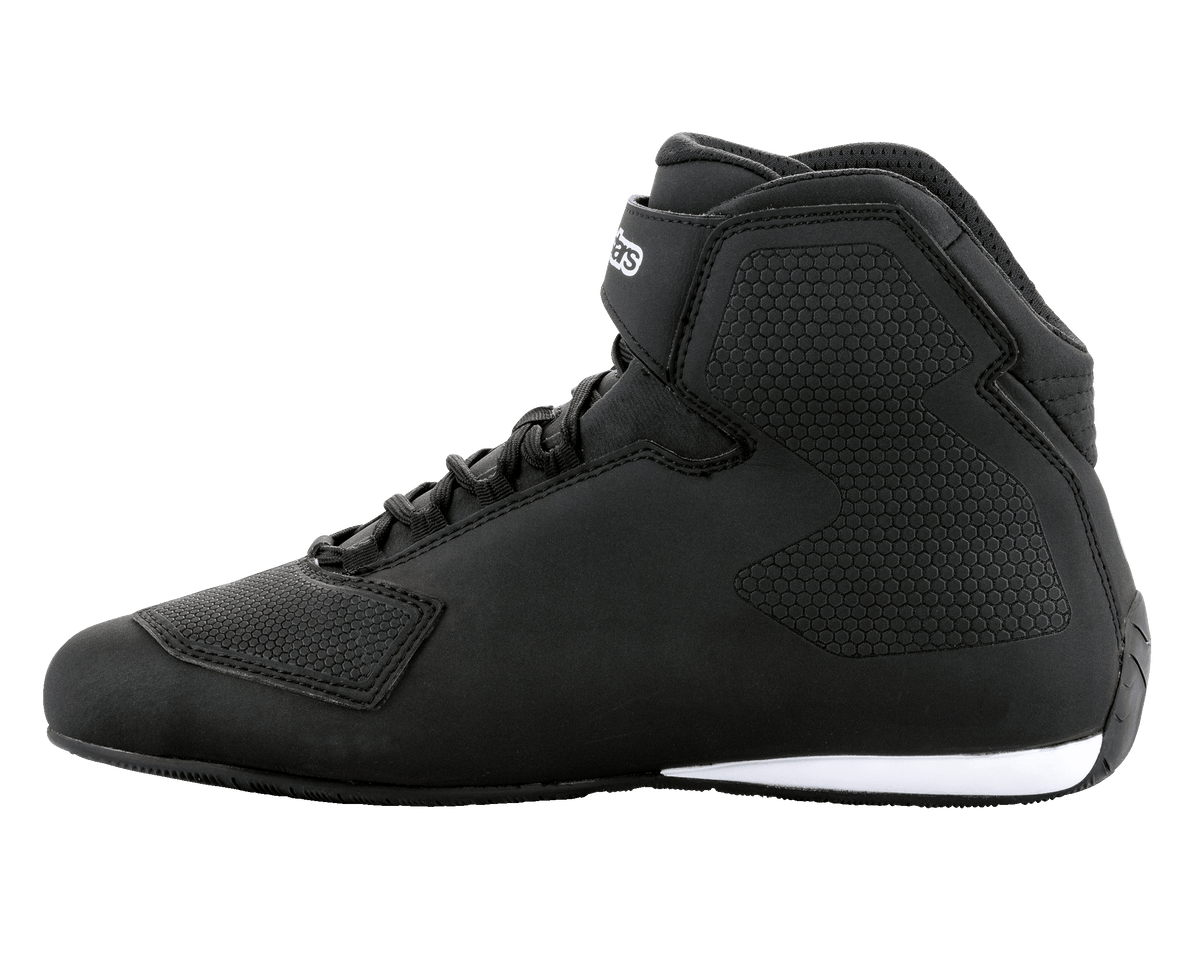 Alpinestars Sektor Shoes, zapatos de motociclismo en negro y blanco, perfil de caña alta, sistema de cordones rápidos con correa en el tobillo, chasis de microfibra texturizada, detalle de suela blanca en el talón, calzado protector elegante para conducción en carretera