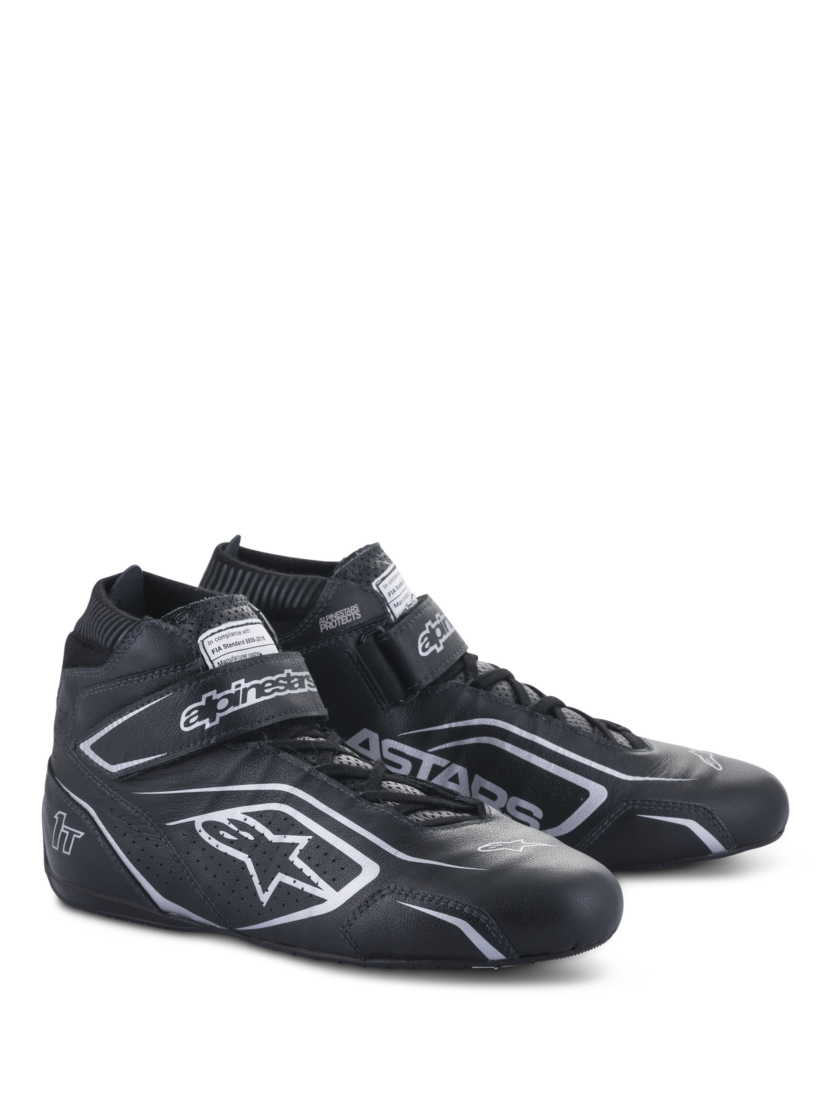 Alpinestars Tech-1 T V3 Shoes FIA, zapatos de automovilismo, negro y plata, confección en cuero de vaca con logotipos y marca Alpinestars en plata, vista lateral en ángulo con correa de gancho y bucle y cierre de cordones