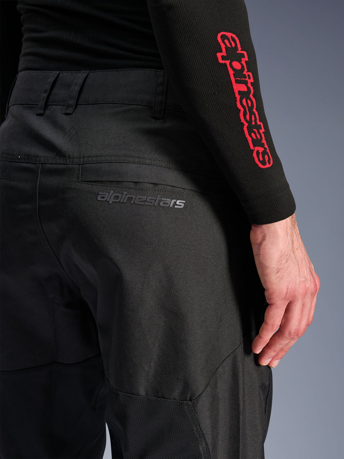 Alpinestars C-1 Air Pants, pantalones de moto textiles negros, primer plano del bolsillo trasero con un sutil logotipo gris de Alpinestars, con paneles de malla transpirable y polifabric duradero, diseñados para la comodidad en la conducción urbana